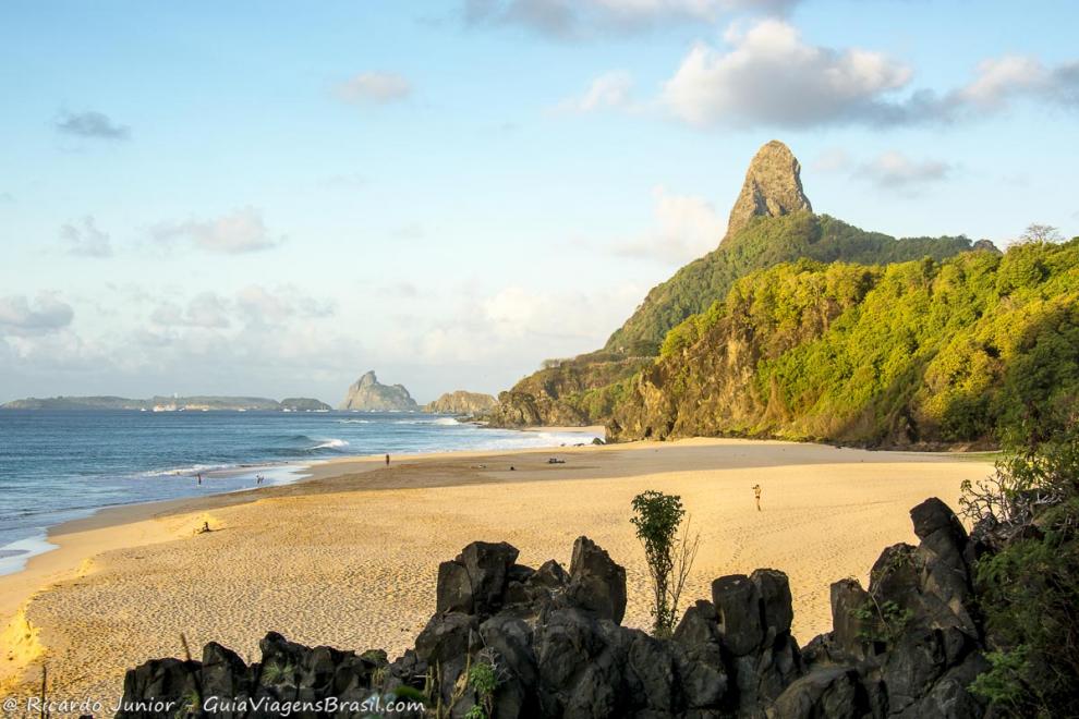 Imagem de umas pedras e ao fundo a Praia Cacimba do Padre.